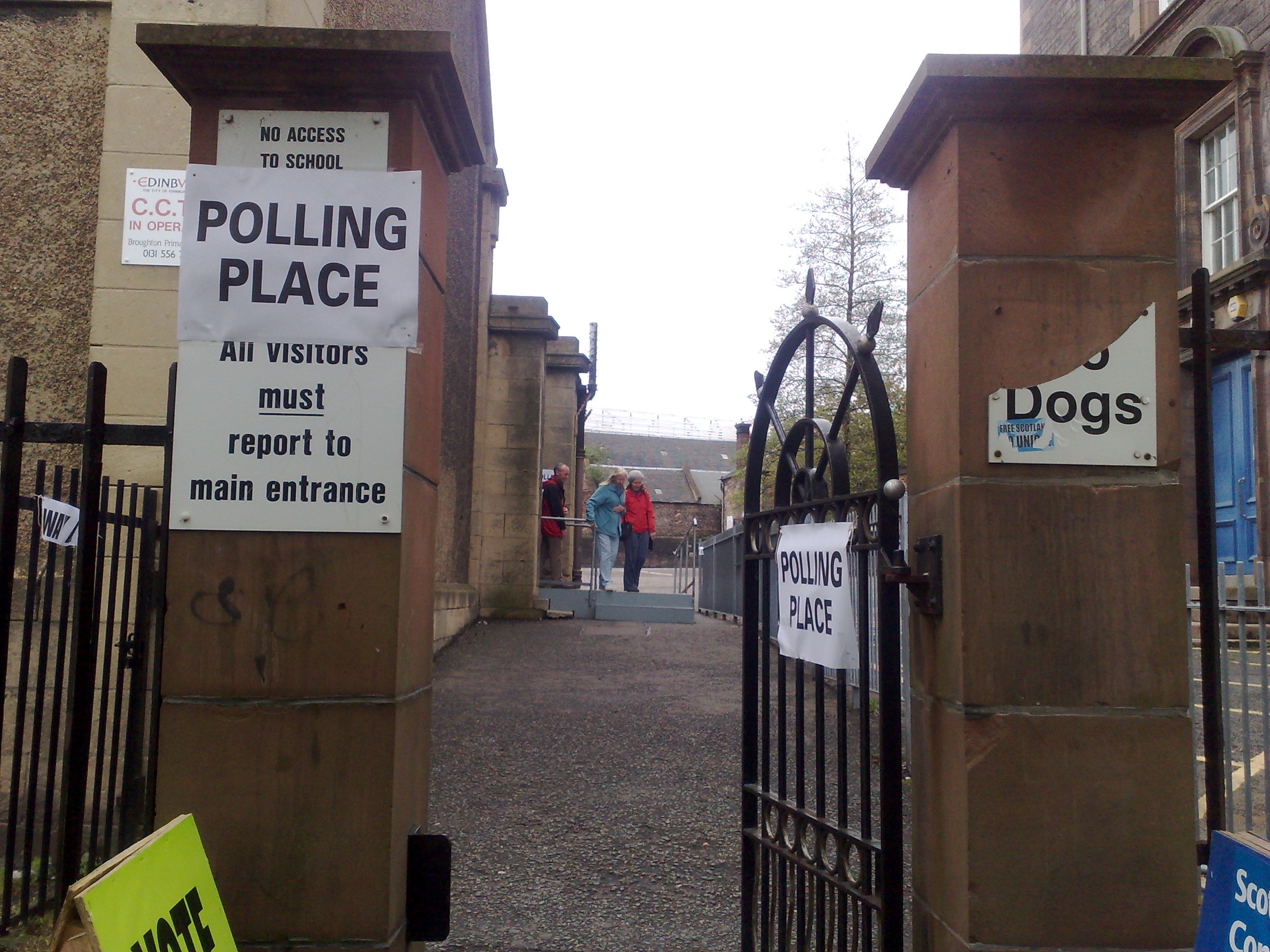 Signs to polling station through gateway with tattered posters