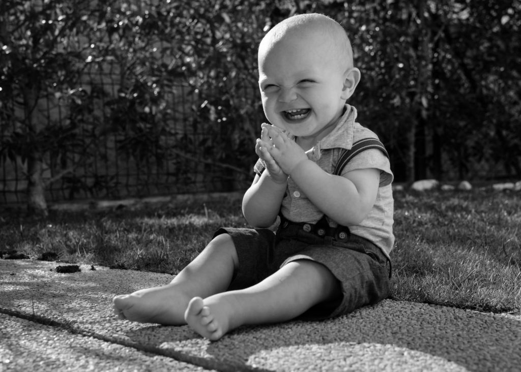 A young child smiling with delight and clapping