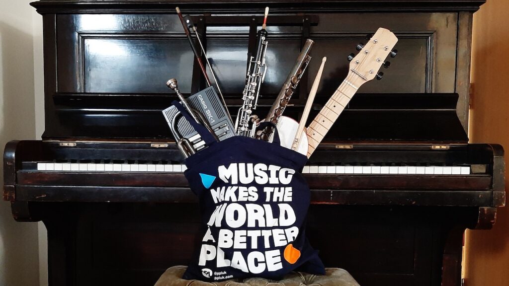 A piano with the PPL tote bag, Music Makes the World a Better Place