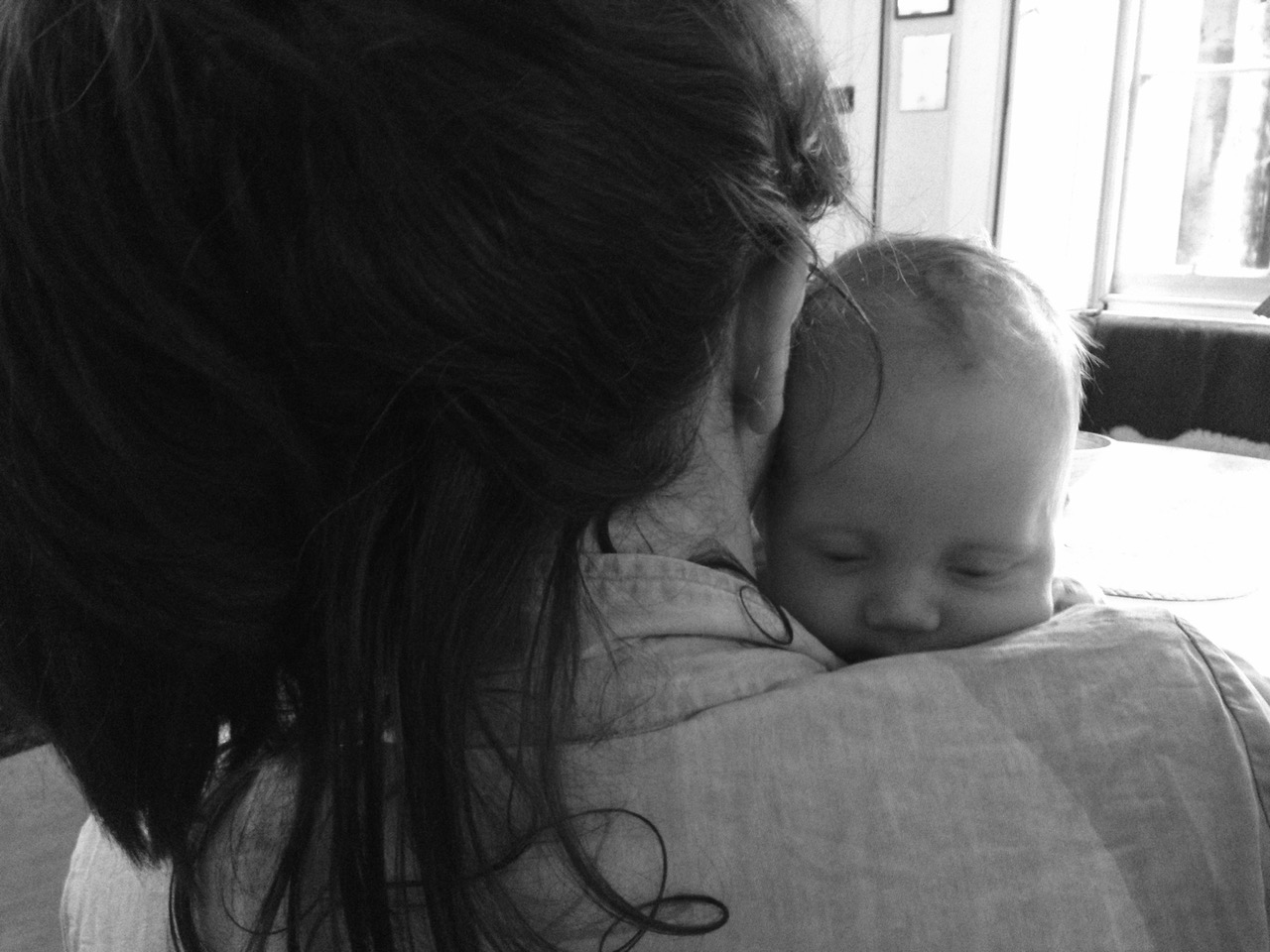 A black and white image of a young mother holding her sleeping baby